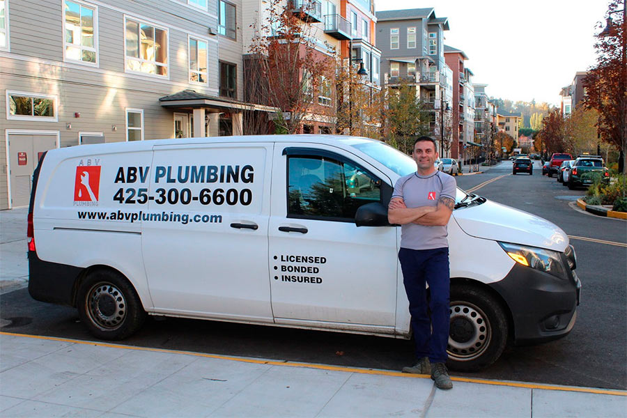 Plumber is standing near his service car.